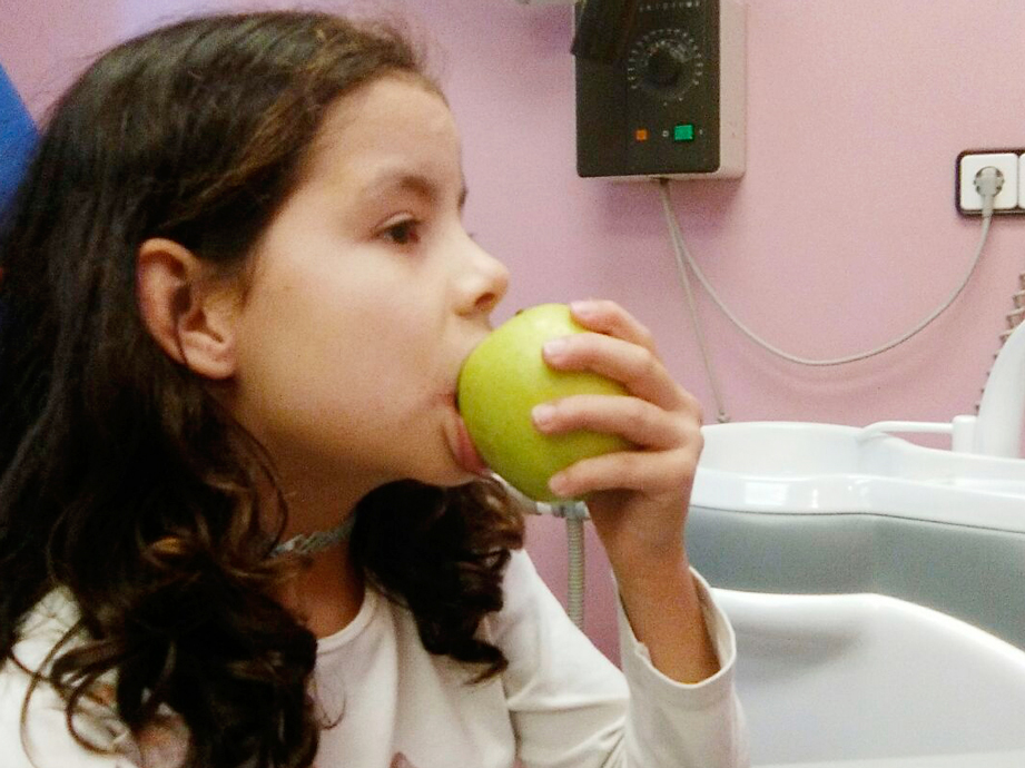 La imagen muestra una joven  adolescente está mordiendo una manzana